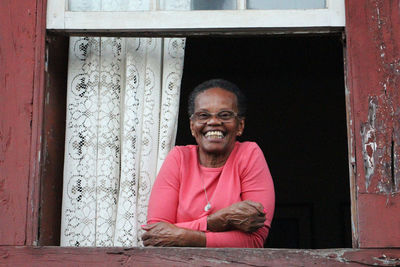 Portrait of smiling woman sitting on window