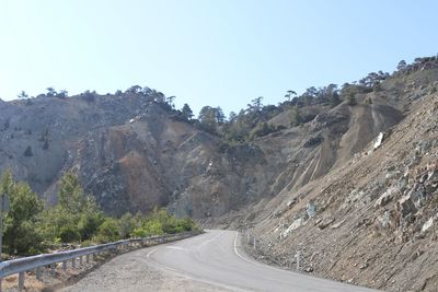 Road leading towards mountains against clear sky