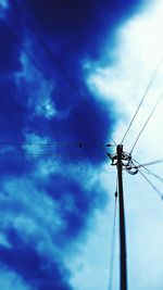 Low angle view of electricity pylon against cloudy sky