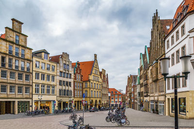 People on street amidst buildings in city against sky