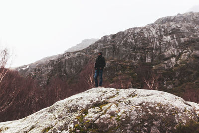 Rear view of man standing on rock against mountain