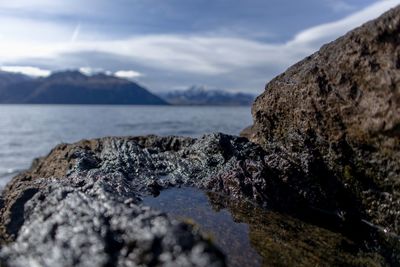 Rocks on shore by sea against sky