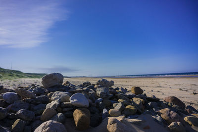 Pebbles on beach against blue sky