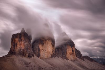 Rock formations on landscape against cloudy sky