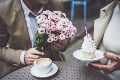 Midsection of woman holding coffee cup on table