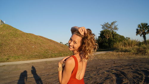 Young woman standing on road against clear sky