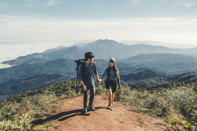 Young couple holding hands while walking on land