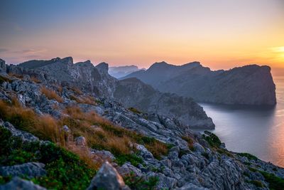 Scenic view of sea and mountains against sky during sunset