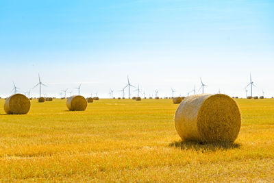 Hay bales on field against clear sky