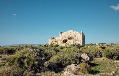 Castle on landscape against clear blue sky