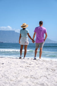 Rear view of couple standing at beach