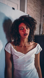 Portrait of young woman standing against black background