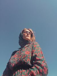 Low angle view of woman standing against blue sky