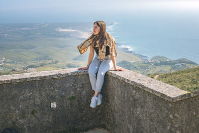 Full length of woman standing on retaining wall