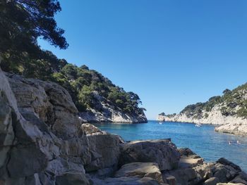 Scenic view of sea and rocks against clear blue sky