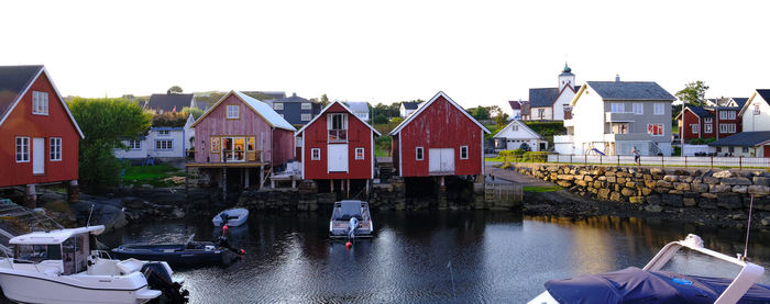 Houses by river amidst buildings against sky