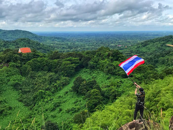 High angle view of man holding flag while standing on mountain