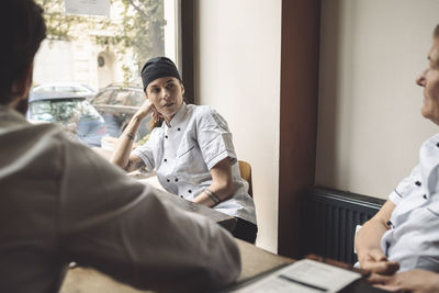 Female chef looking at coworker in restaurant