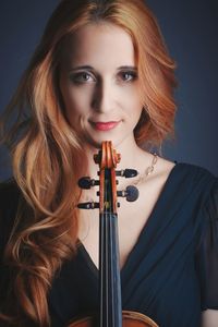 Portrait of young woman with violin against colored background