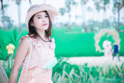 Portrait of beautiful young woman standing against plants