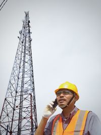 Low angle view of man using mobile phone against sky