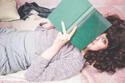 Woman reading book on bed at home