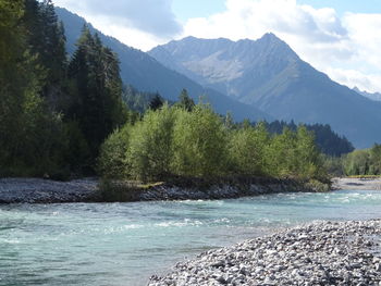 Scenic view of river and mountains against sky