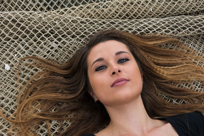 Portrait of beautiful young woman lying on net