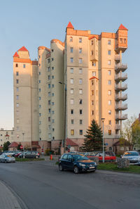 Cars on road by buildings against sky in city