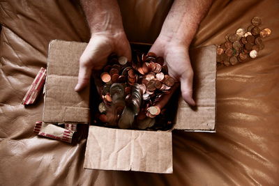 Cropped hand of man putting us coins in cardboard box