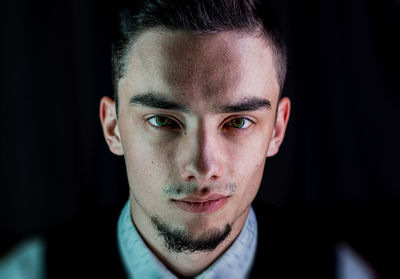 Close-up portrait of young man against black background