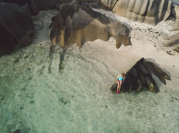 Woman sitting on rock in sea