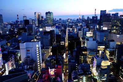 High angle view of illuminated city buildings against sky at dusk