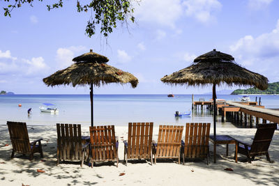 Deck chairs on beach against sky