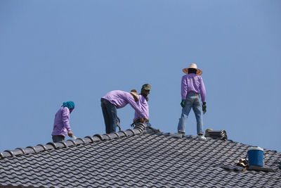 Low angle view of people on roof against building