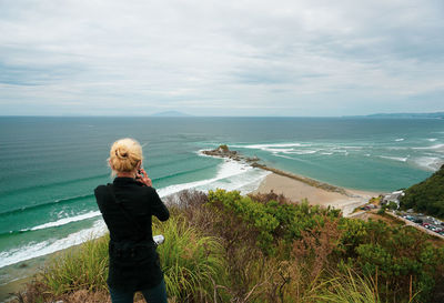 A woman hikes at mangawhai heads reserve in northland, new zealand.