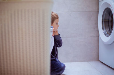 Side view of boy looking through wall