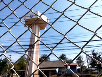 Chainlink fence by building against sky