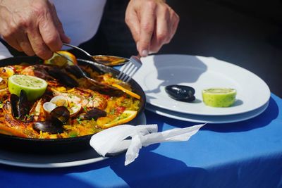 Midsection of man eating food at table