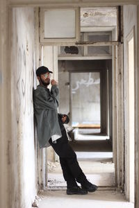 Side view of young man standing in corridor