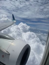 Airplane flying over clouds against sky