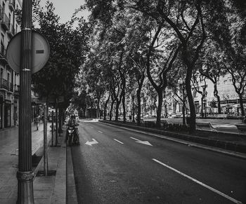 Road amidst trees in city against sky