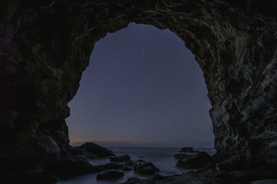 Rock formations by sea against sky at night