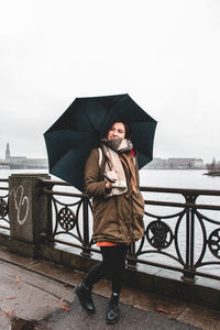 Full length of man standing on railing against sky during winter