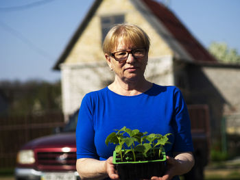 Portrait of man wearing eyeglasses while standing against plants