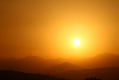 Scenic view of silhouette mountains against orange sky