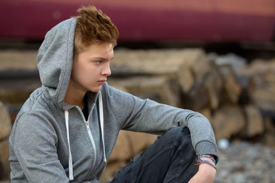 Midsection of man looking away while sitting outdoors