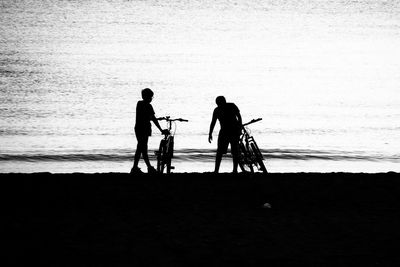 Silhouette men standing at beach against sky