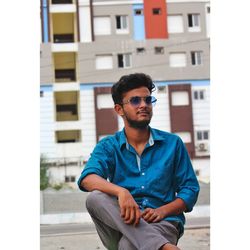 Portrait of young man standing against building