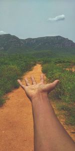 Midsection of person hand on landscape against sky